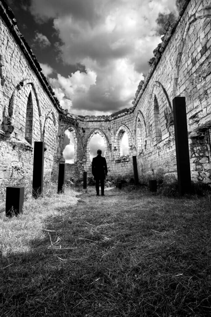 photo noir et blanc florent création un homme dans une chapelle en ruine regarde le ciel entouré de colonnes noires boulogne sur mer